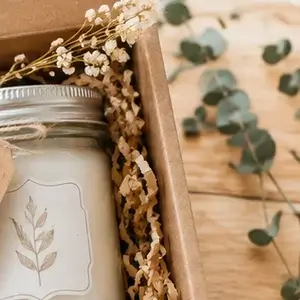 Vela artesanal dentro de una caja de regalo con flores secas y ramas de eucalipto